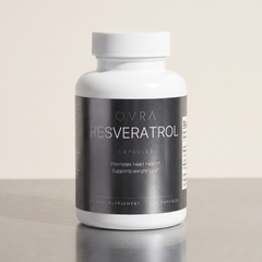 OVRA Resveratrol bottle on brushed steel, bone-white studio background